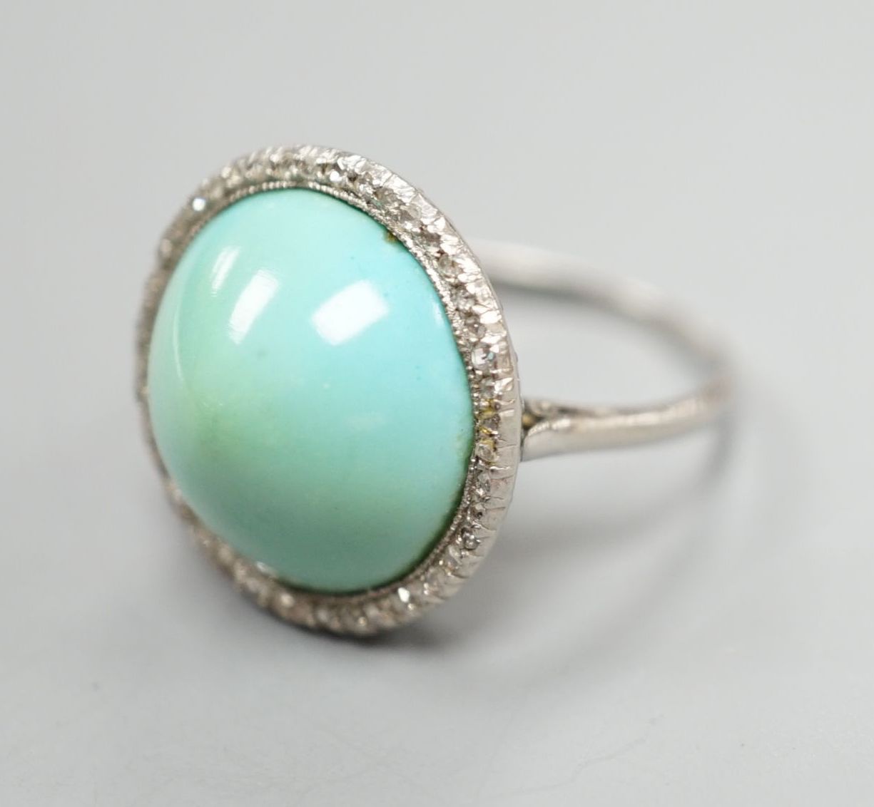 A white metal cabochon turquoise and diamond chip set dress ring, size J/K, gross 6.9 grams.